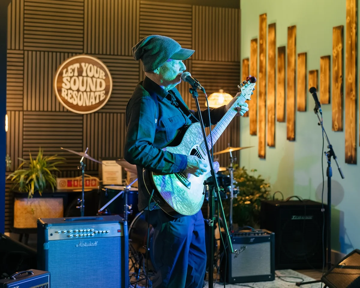 Solo performer with guitar on the Resonate lounge stage at the After Hours Open Jam